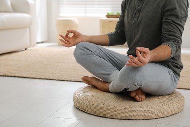 Man meditating on wicker mat at home, closeup