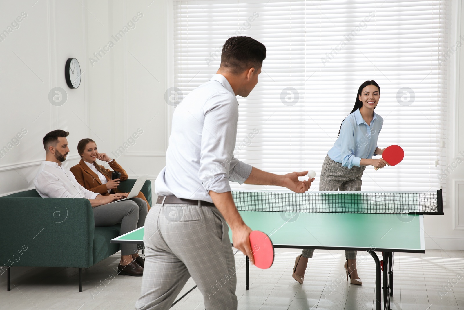 Photo of Business people playing ping pong in office