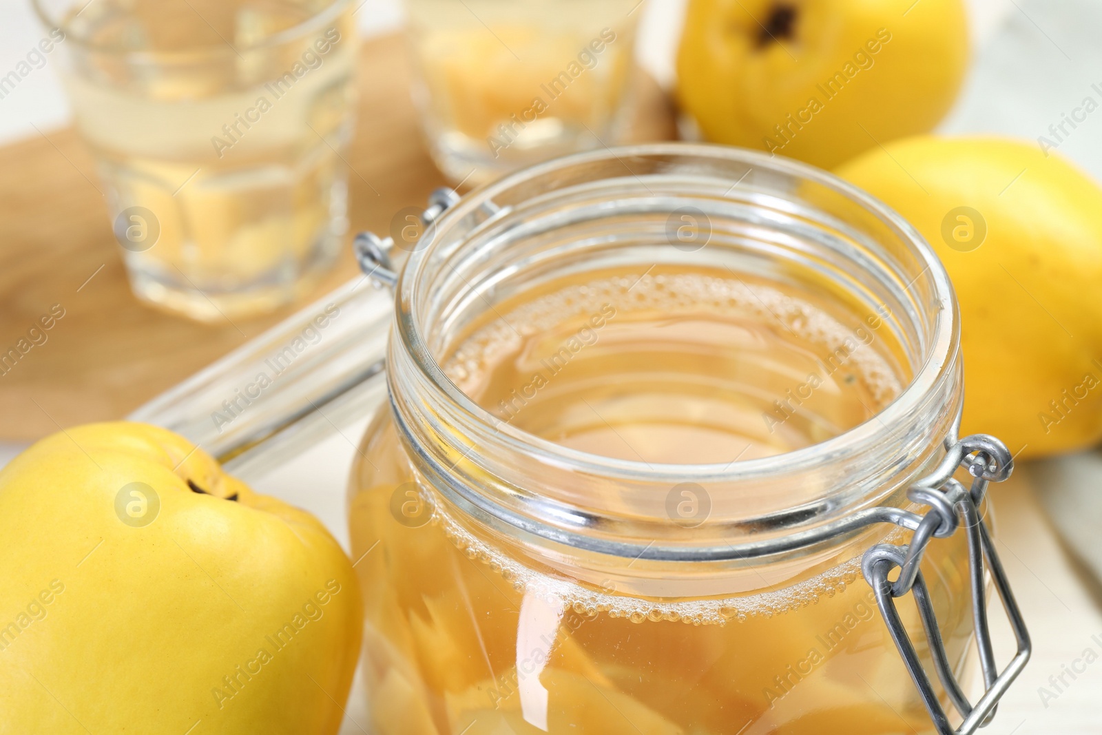 Photo of Delicious quince drink in glass jar and fresh fruits on table, closeup