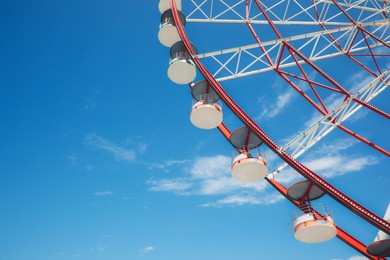 Photo of Beautiful large Ferris wheel against blue sky, low angle view