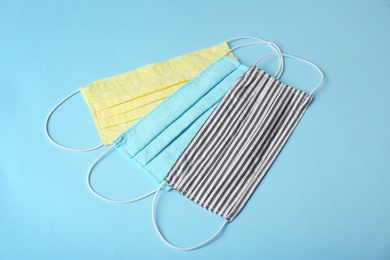 Photo of Homemade protective face masks on light blue background