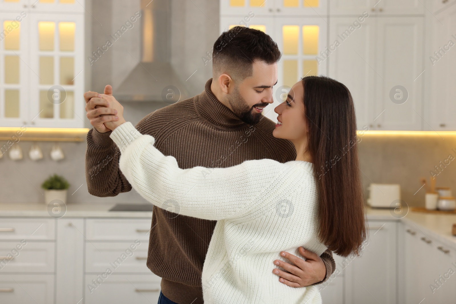 Photo of Affectionate young couple dancing in light kitchen