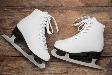Photo of Pair of white ice skates on wooden background, flat lay