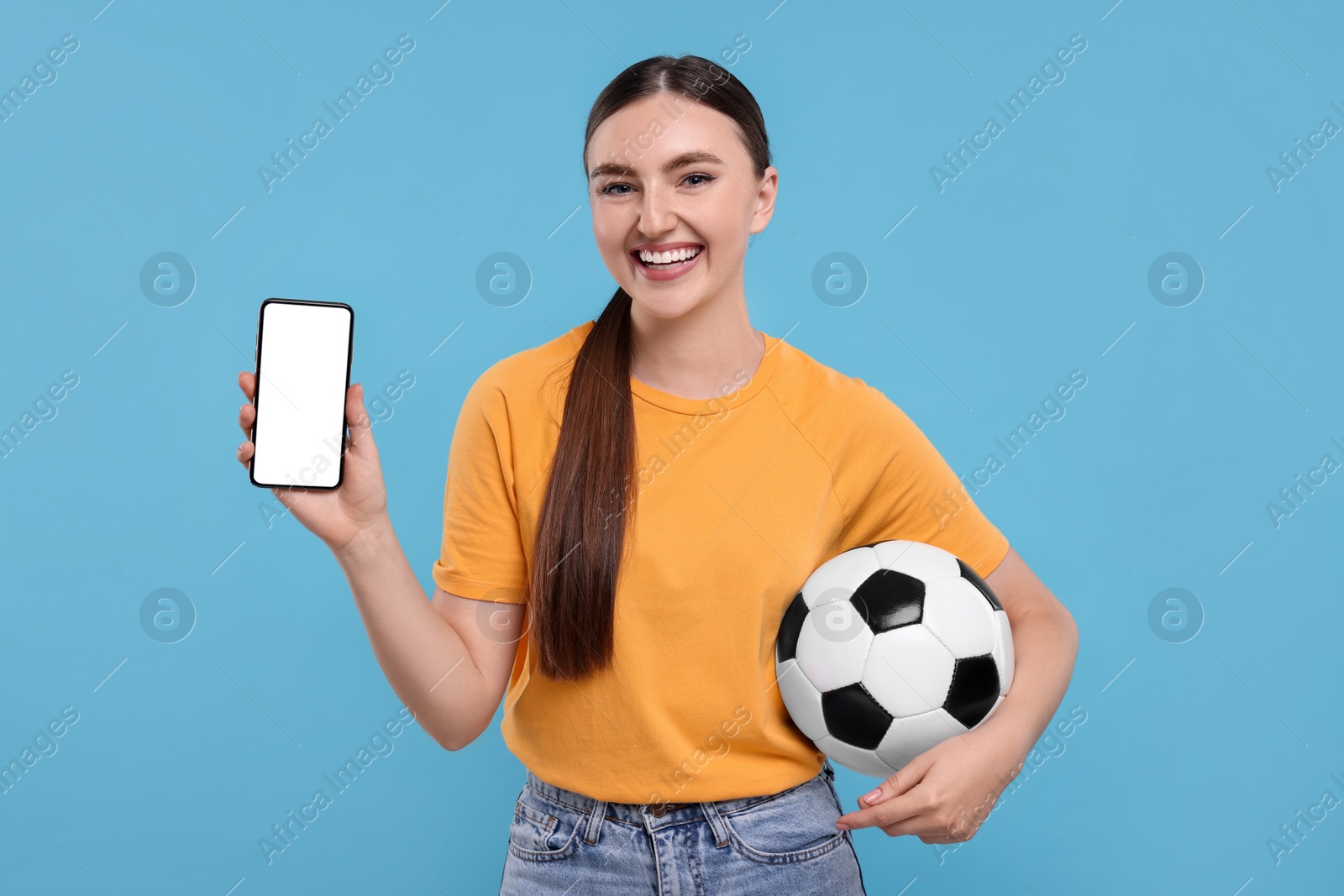 Photo of Happy soccer fan with ball showing smartphone on light blue background