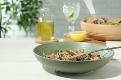 Photo of Delicious salad with beef tongue, vegetables and fork on white wooden table. Space for text