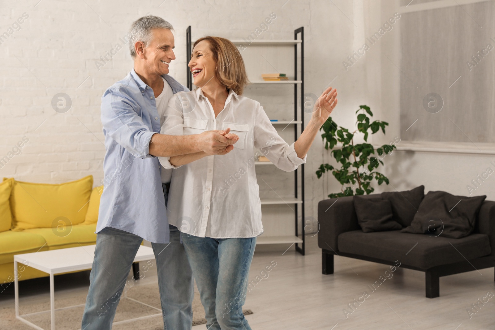 Photo of Happy senior couple dancing together in living room