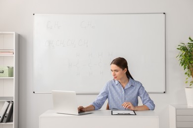 Photo of Young chemistry teacher giving lesson at table in classroom