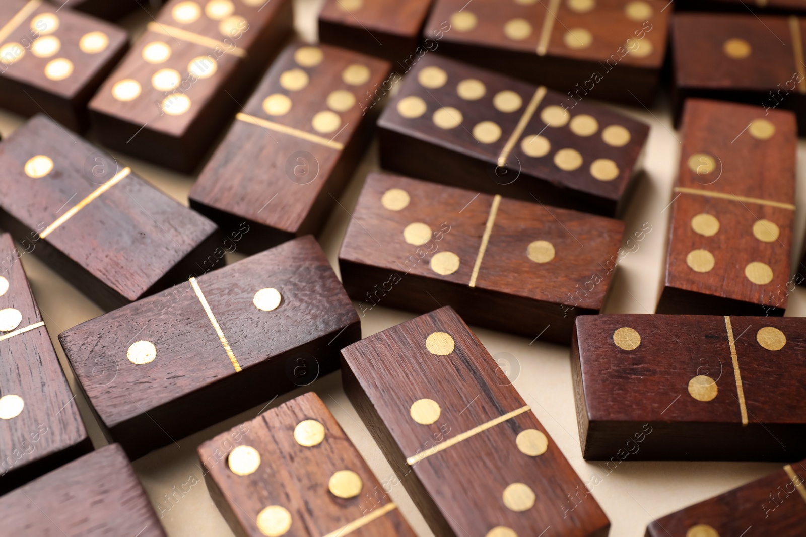 Photo of Wooden domino tiles on beige background, closeup