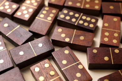 Wooden domino tiles on beige background, closeup