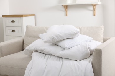 Photo of Soft pillows and duvet on sofa indoors