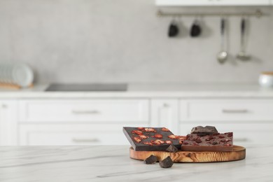 Photo of Delicious chocolate on white marble table in kitchen. Space for text