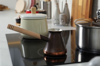 Photo of Cezve and pots on electric stove in kitchen. Cooking utensils