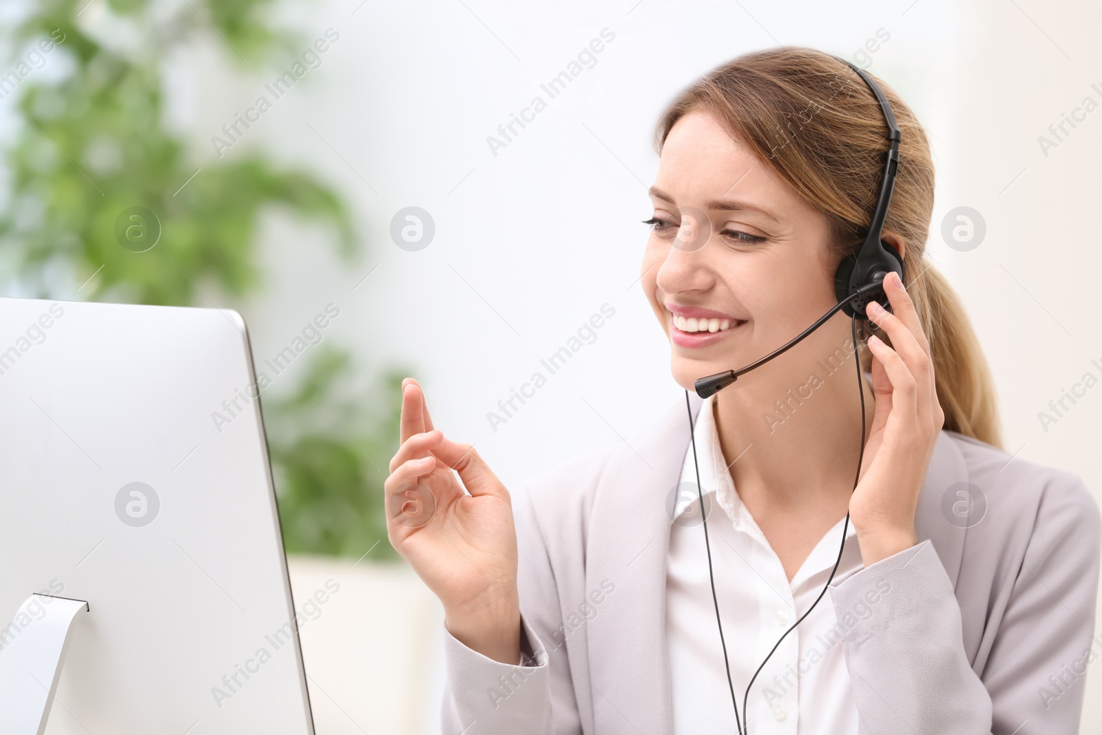 Photo of Young female receptionist with headset in office