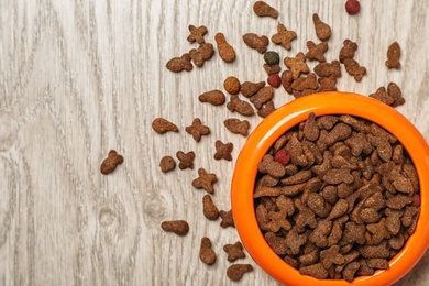 Photo of Bowl with food for cat or dog on wooden background. Pet care