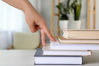 Woman imitating stepping up on books with her fingers indoors, closeup