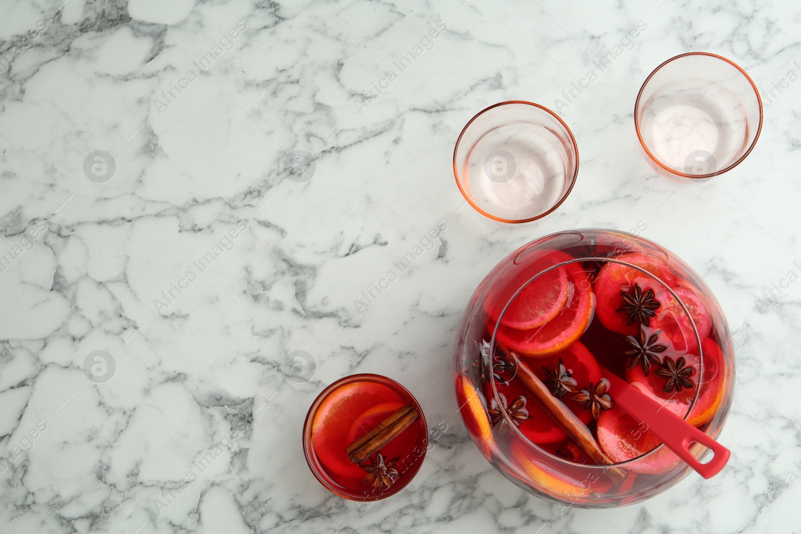 Photo of Delicious aromatic punch drink and glasses on white marble table, flat lay. Space for text