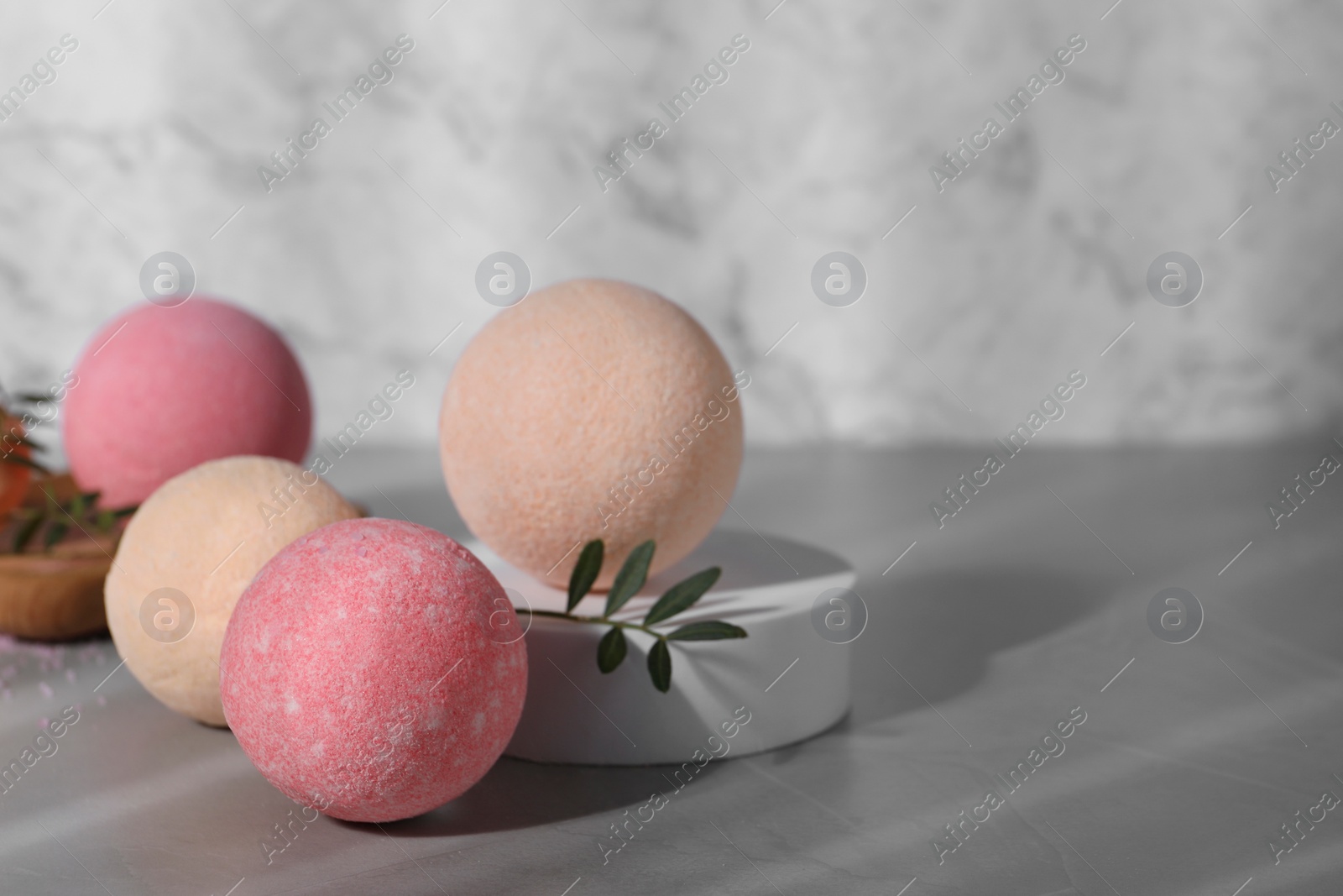 Photo of Beautiful aromatic bath bombs and green twig on grey table, space for text