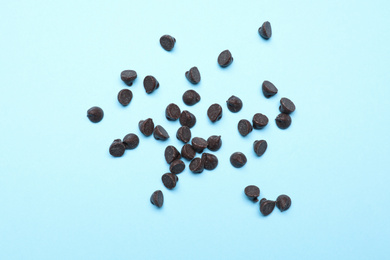 Delicious dark chocolate chips on light blue background, top view