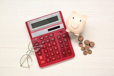 Photo of Calculator, piggy bank, coins and glasses on white wooden table, flat lay