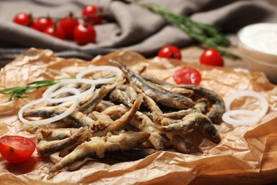 Photo of Delicious fried anchovies with onion rings and tomatoes served on table, closeup