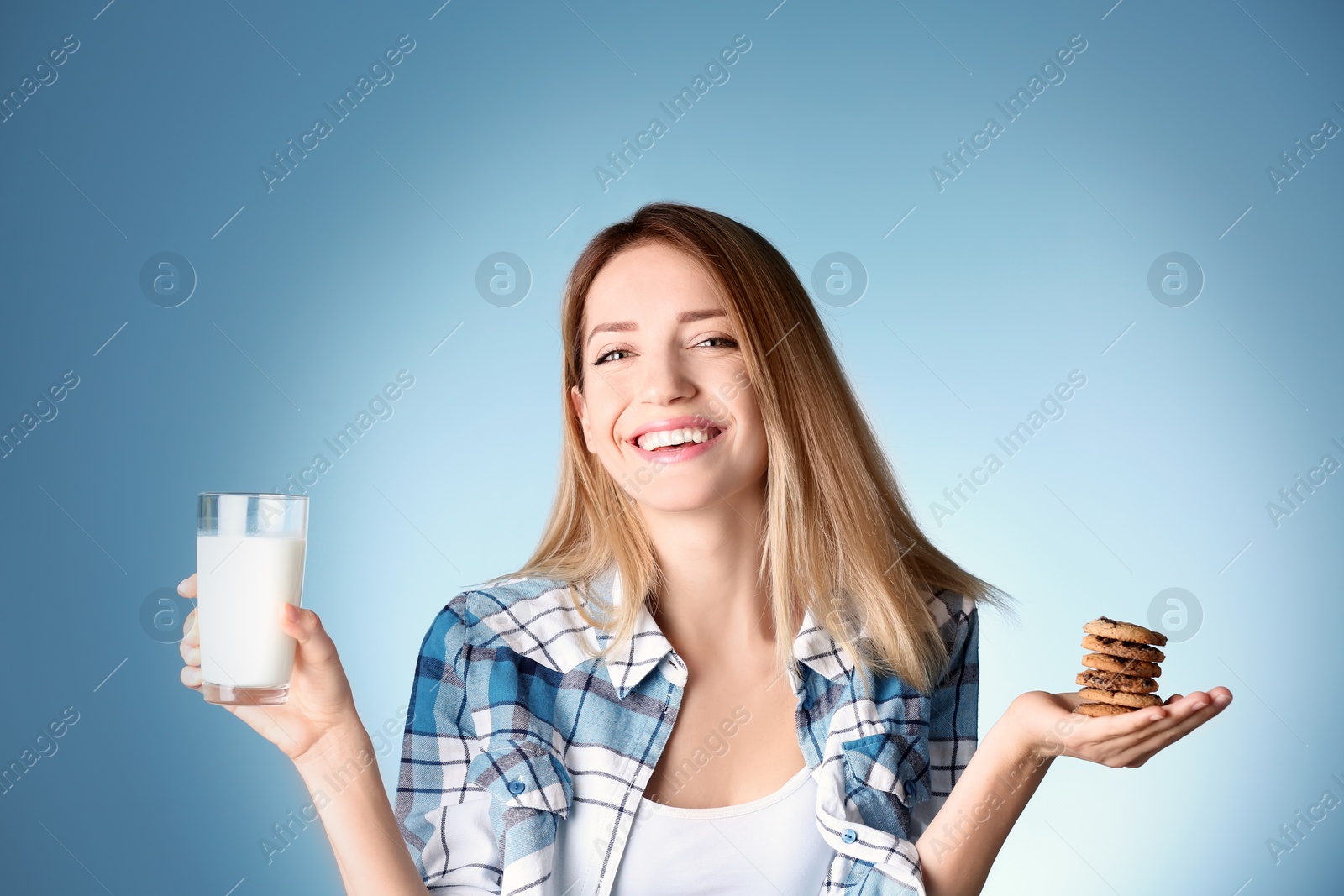 Photo of Beautiful young woman drinking milk with cookies on color background