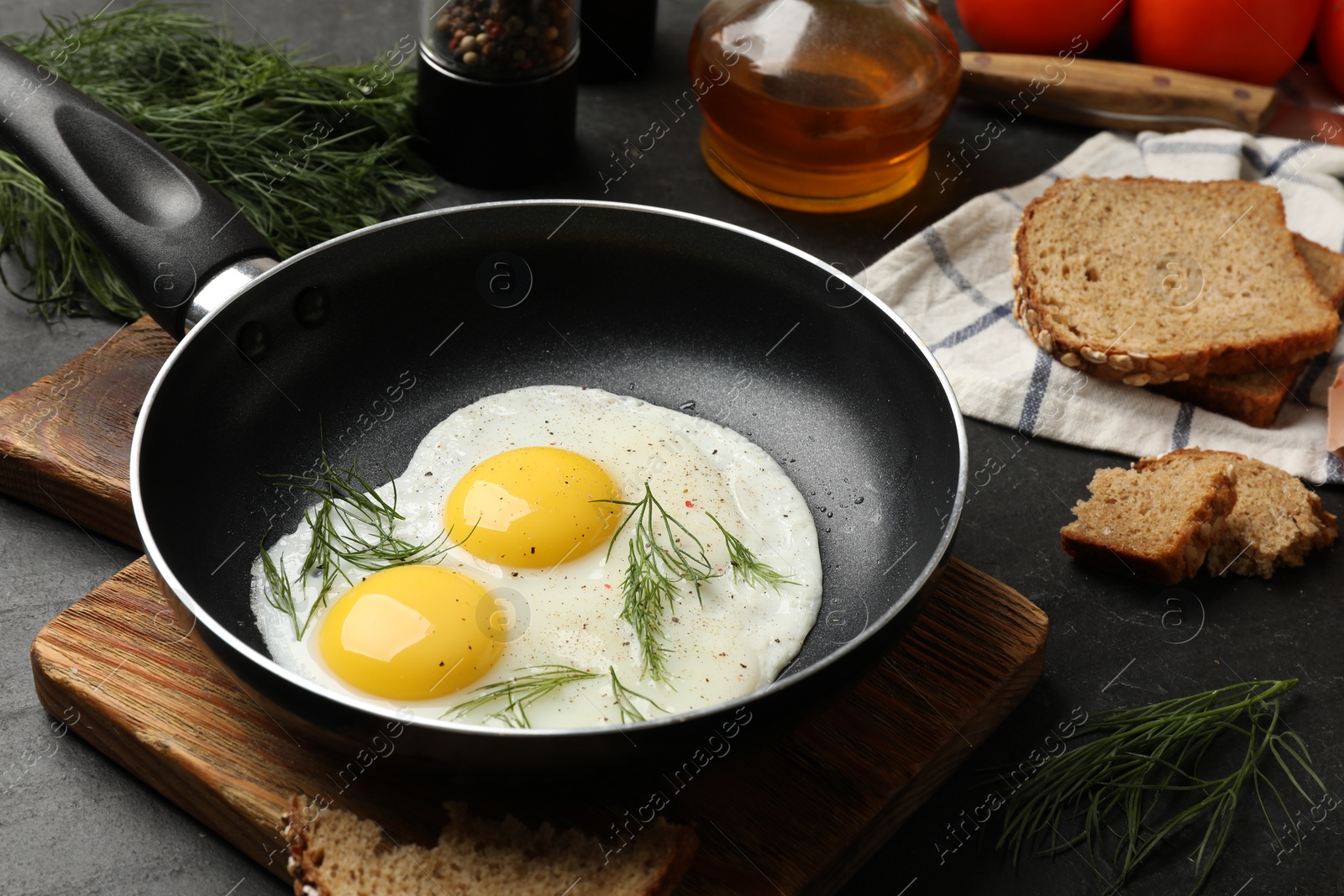 Photo of Frying pan with tasty cooked eggs and other products on black table