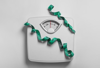 Photo of Weight loss concept. Scales and measuring tape on white background, top view