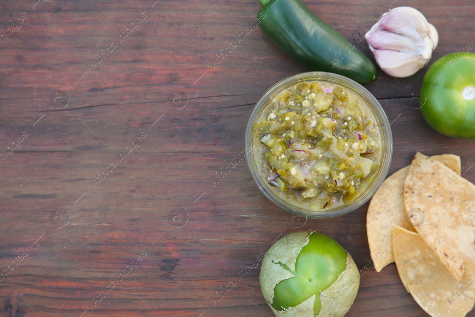 Photo of Tasty salsa sauce, ingredients and tortilla chips on wooden table, flat lay. Space for text