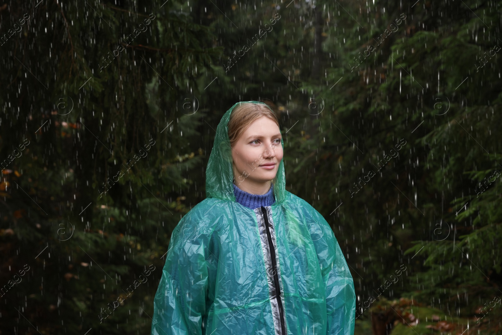 Photo of Young woman with raincoat in forest under rain