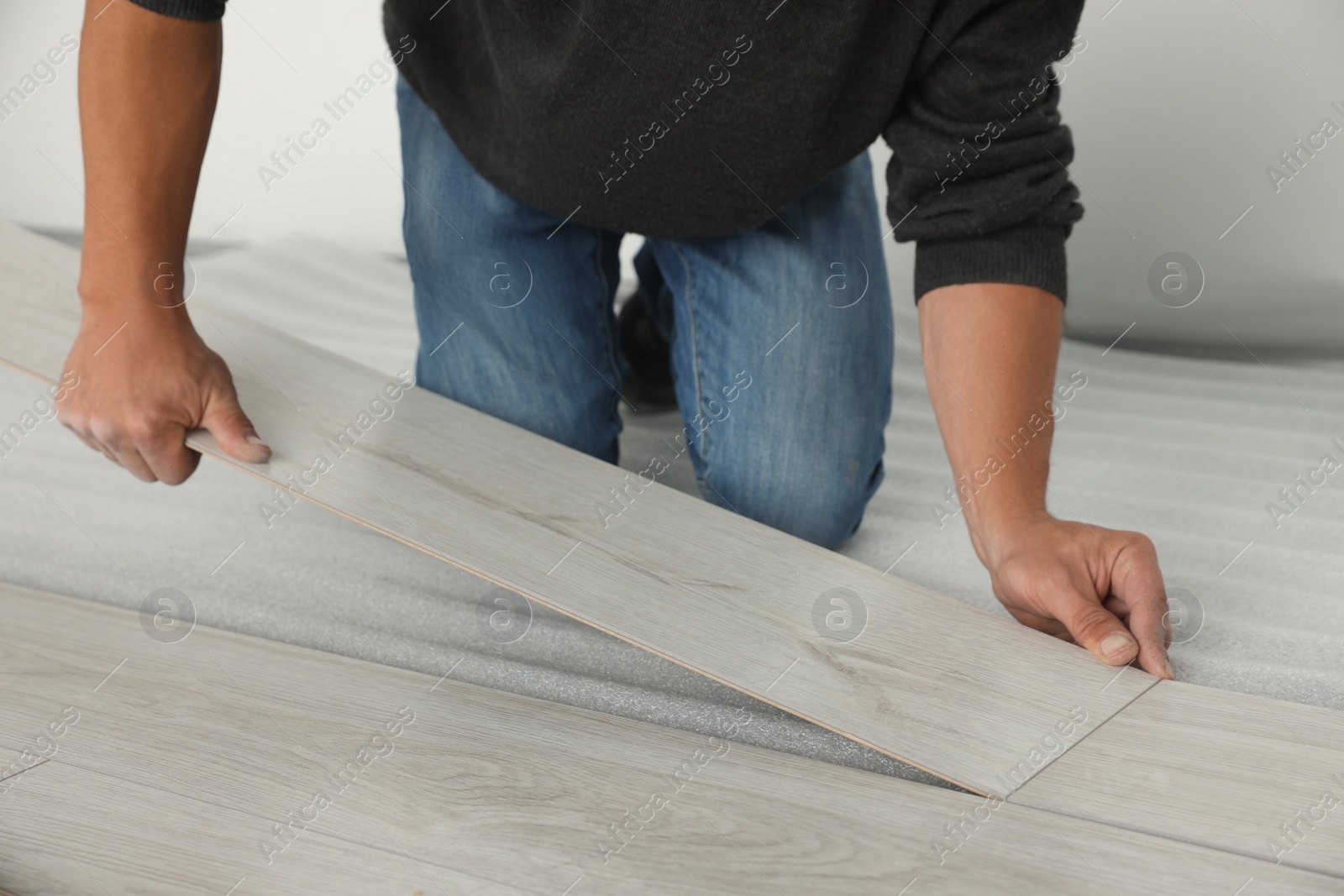 Photo of Worker installing new laminate flooring in room, closeup