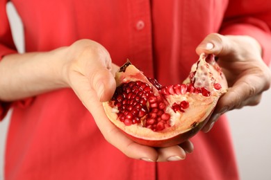 Photo of Woman holding ripe pomegranate on light background, closeup