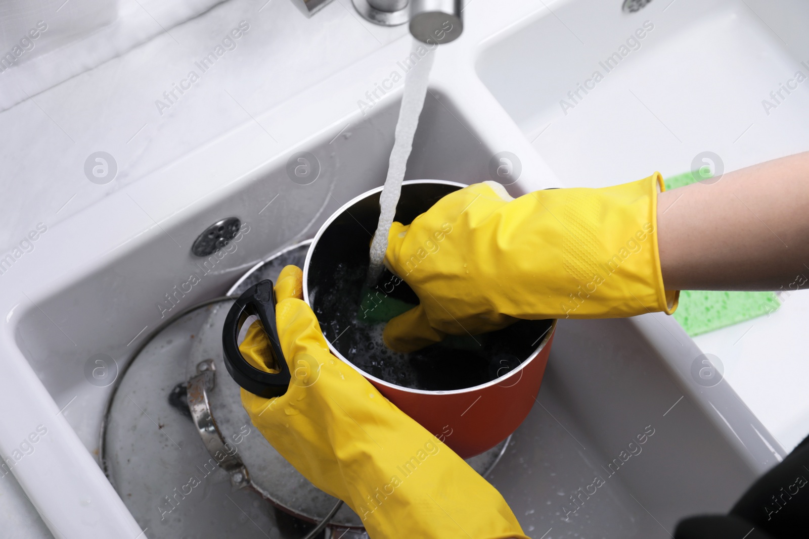 Photo of Woman washing dirty dishes in kitchen sink, closeup