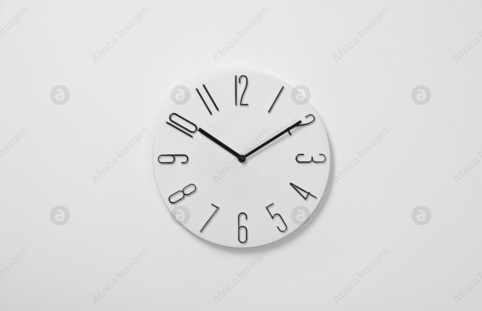 Photo of Stylish analog clock hanging on white wall