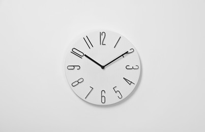 Stylish analog clock hanging on white wall