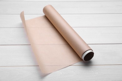 Photo of Roll of baking paper on white wooden table