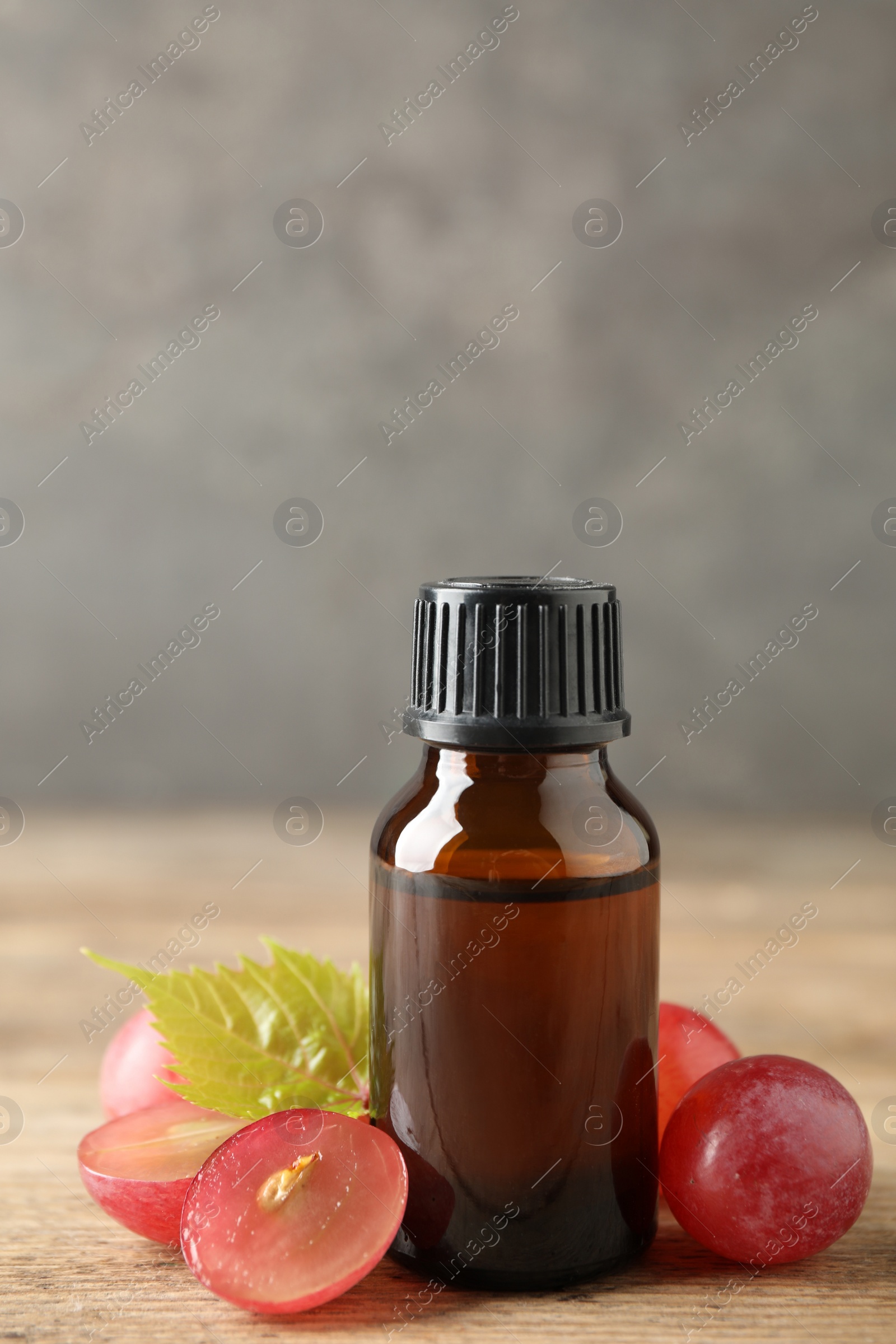 Photo of Bottle with natural grape seed oil on wooden table. Organic cosmetic