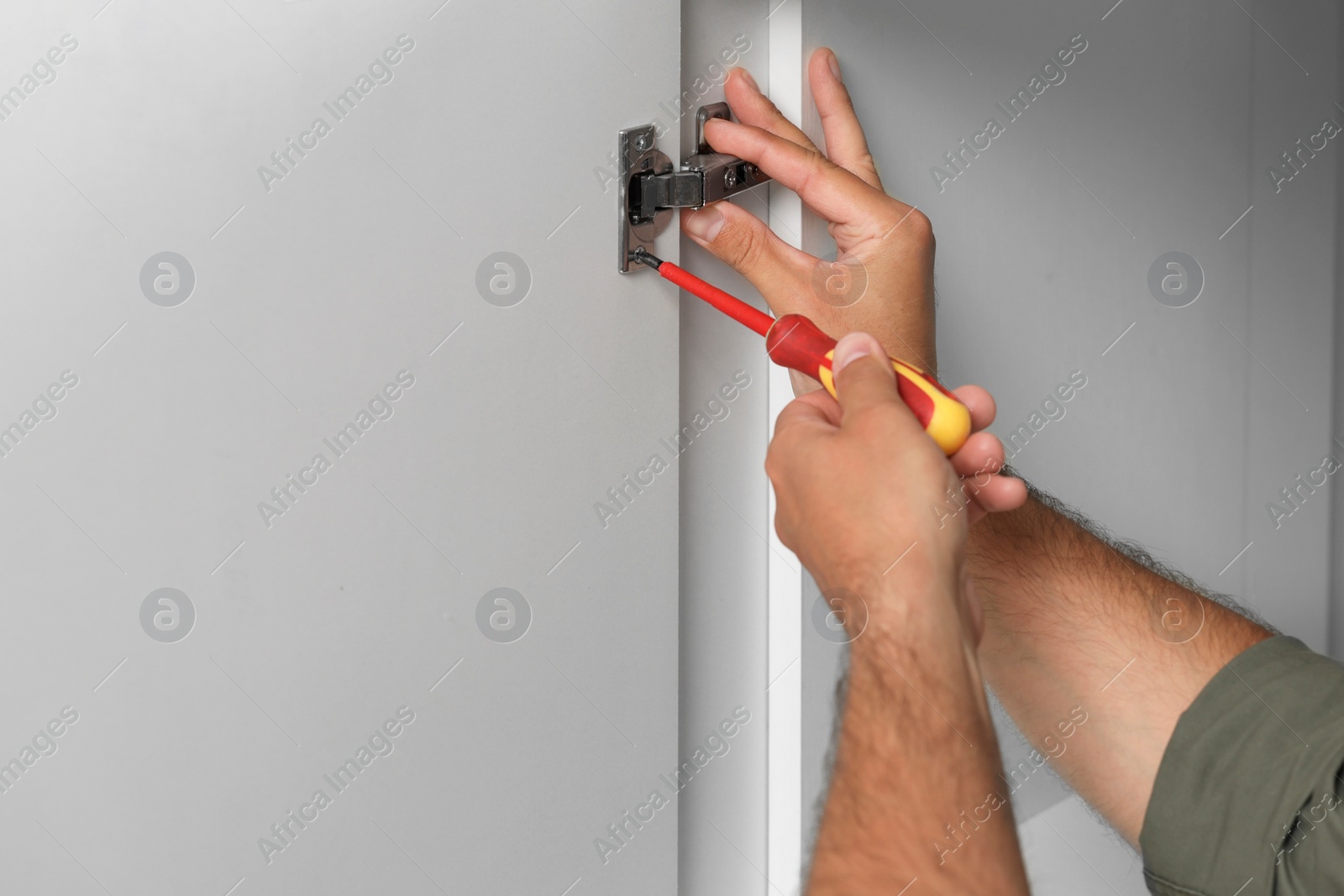 Photo of Man with electric screwdriver assembling furniture, closeup