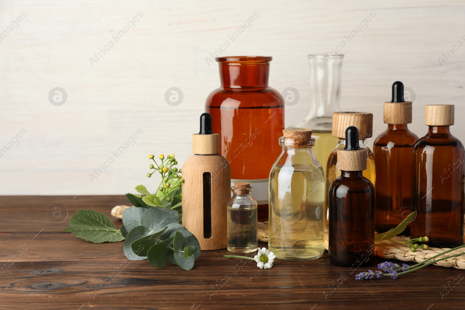 Photo of Aromatherapy. Different essential oils, eucalyptus leaves and flowers on wooden table