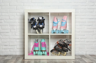 Photo of Pairs of roller skates on shelves near white brick wall