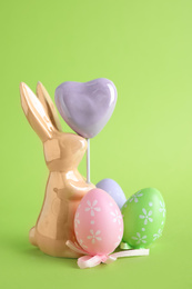 Photo of Easter bunny figure and dyed eggs on green background