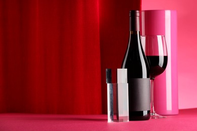 Photo of Stylish presentation of delicious red wine in bottle and glass on color background. Space for text