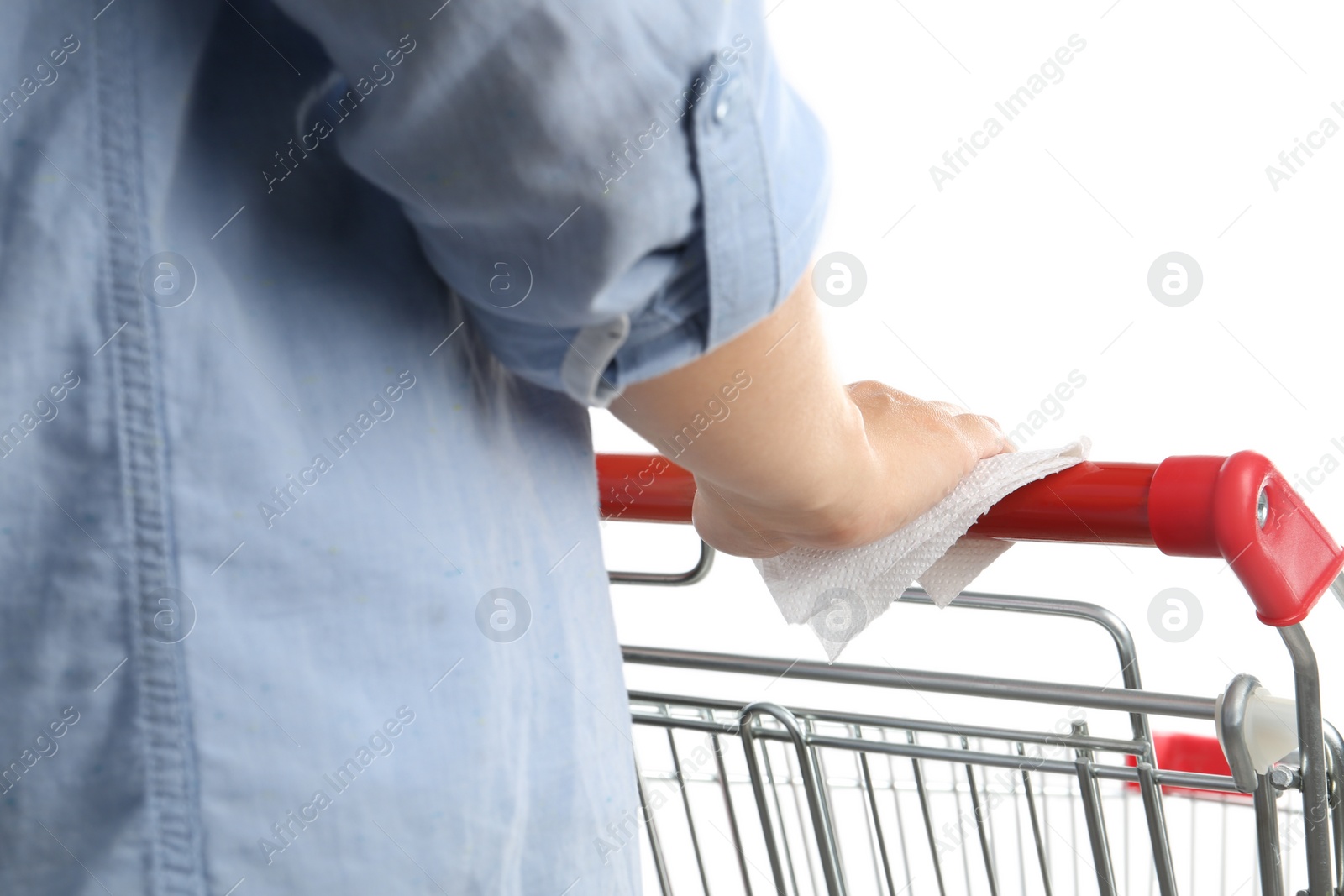 Photo of Woman holding shopping cart handle with tissue paper on white background, closeup