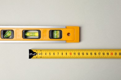 Photo of Building level and tape measure on beige background, top view