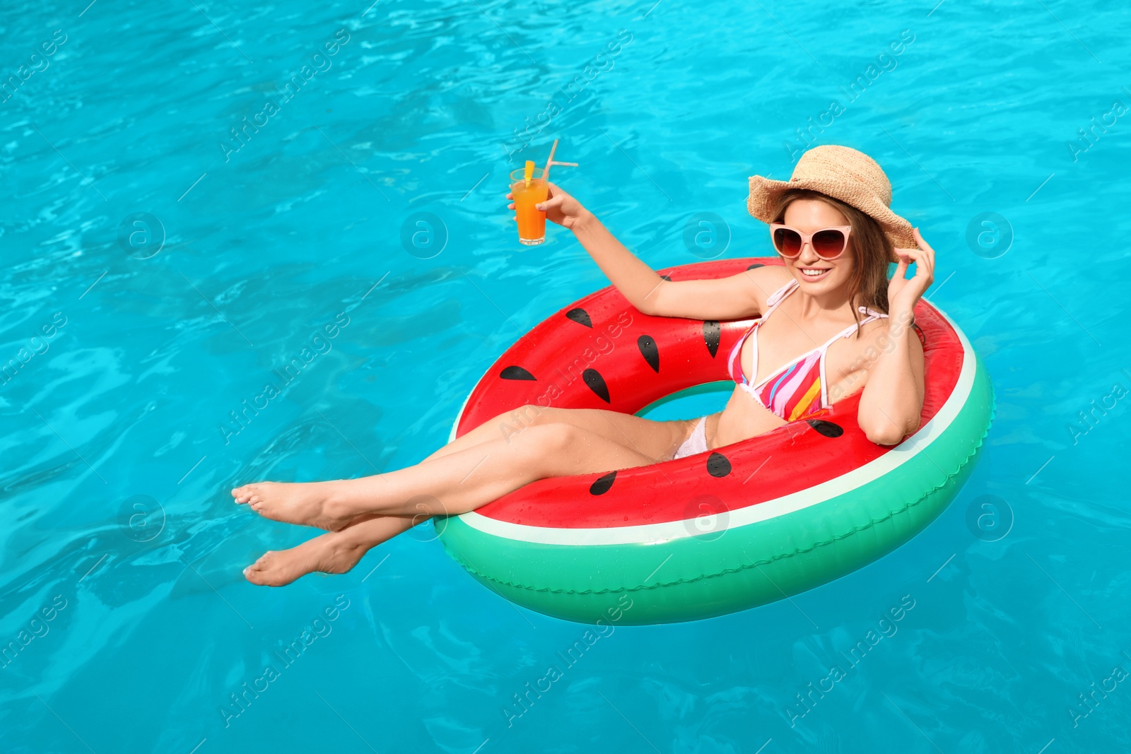 Photo of Young woman with cocktail in pool on sunny day