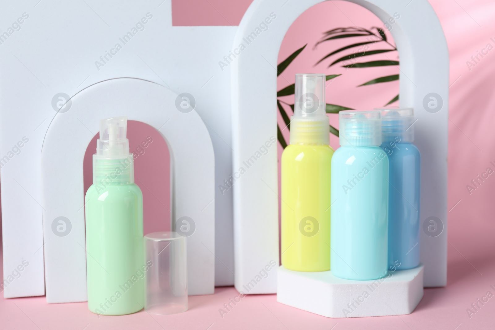 Photo of Cosmetic travel kit and geometric figures on pink background. Bath accessories