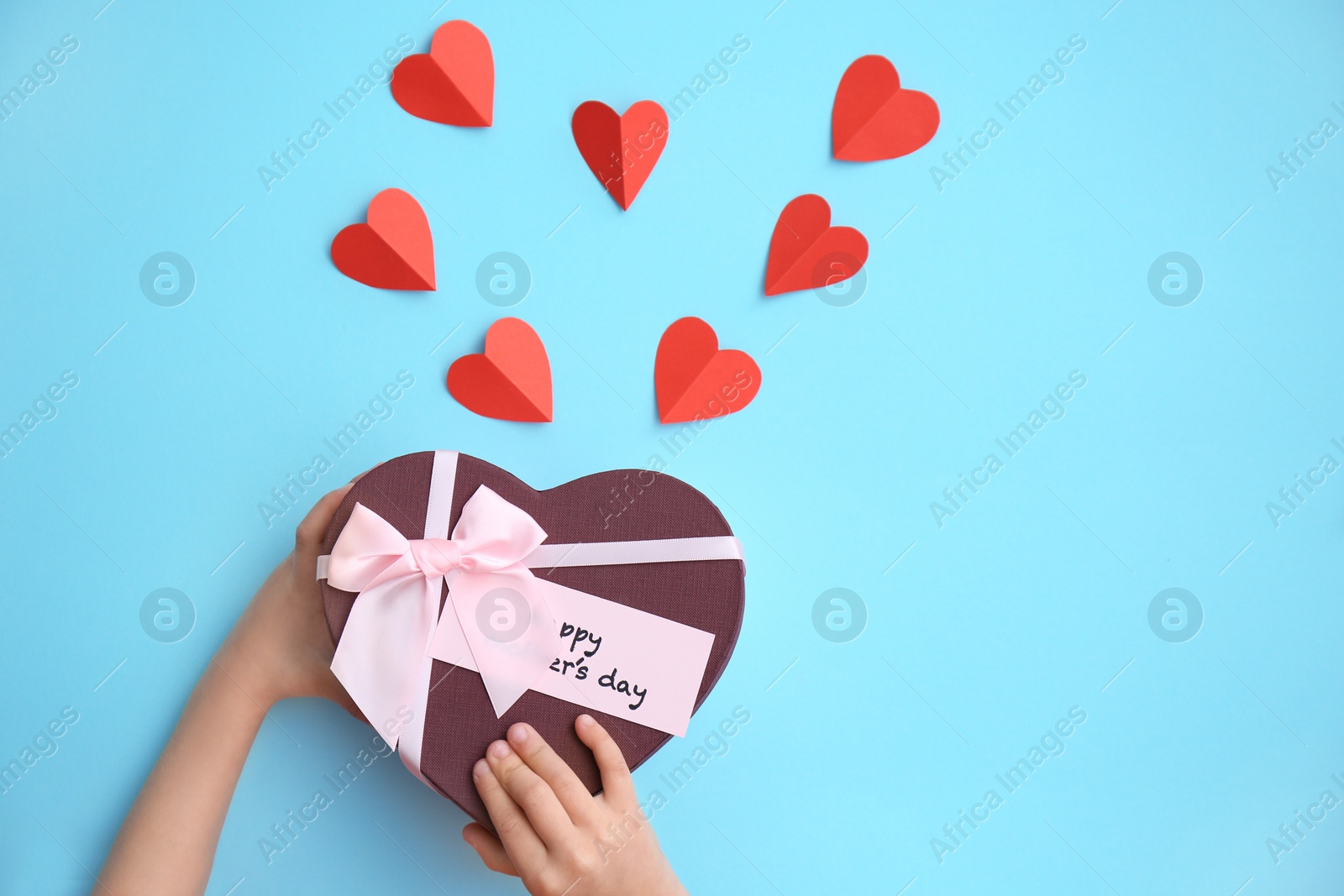 Photo of Child holding gift box for Mother's Day on color background