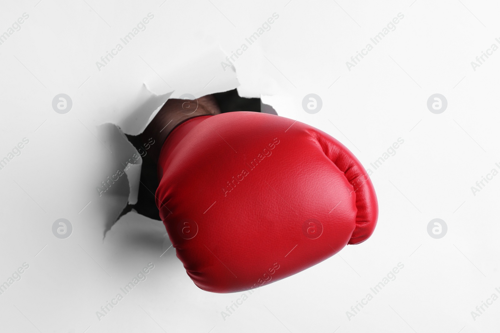 Photo of Man breaking through white paper with boxing glove, closeup