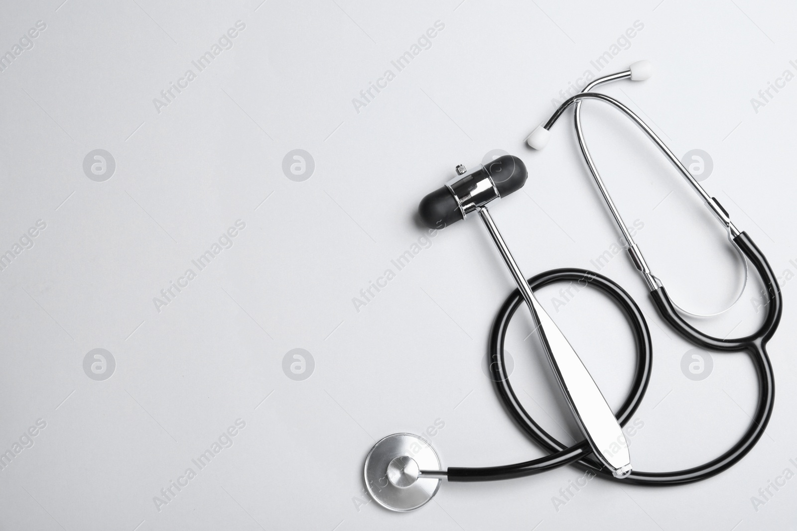 Photo of Reflex hammer with stethoscope on white background, flat lay and space for text. Nervous system diagnostic