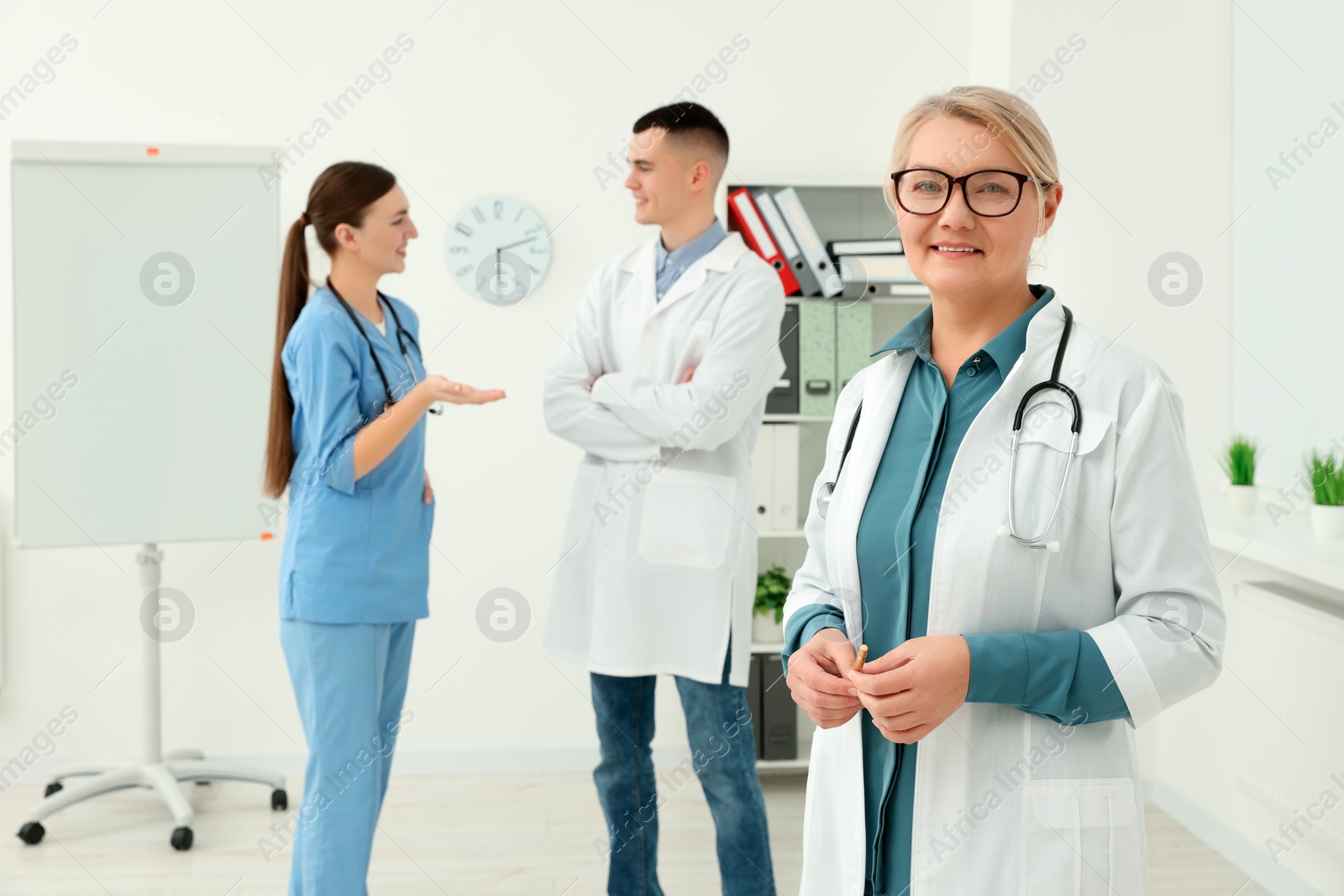 Photo of Portrait of doctor near colleagues in clinic