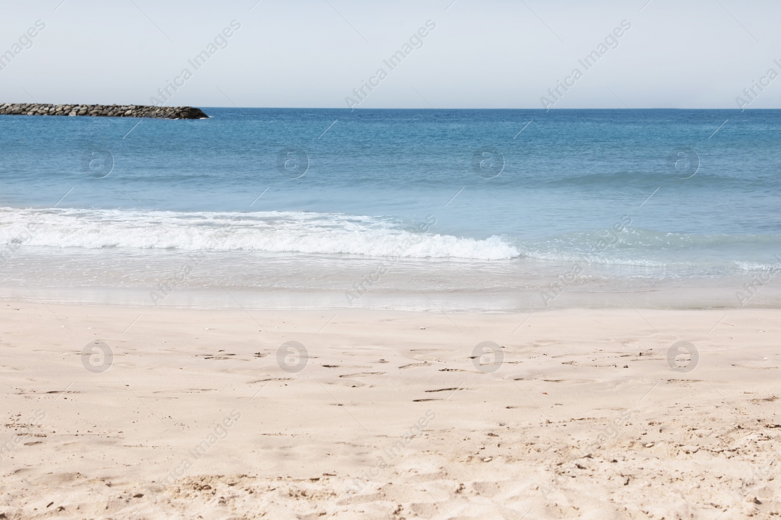 Photo of Picturesque view of beautiful beach with stone breakwater on sunny day